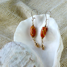 Earrings with oval-shaped wood bead and handpainted orange and gold swirl-pattern beads