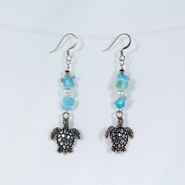 Earrings featuring sea turtles, faux pearls, turquoise-coloured chip beads, and silver trim