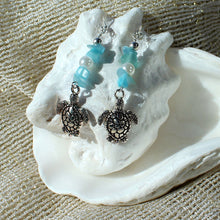 Earrings featuring sea turtles, faux pearls, turquoise-coloured chip beads, and silver trim